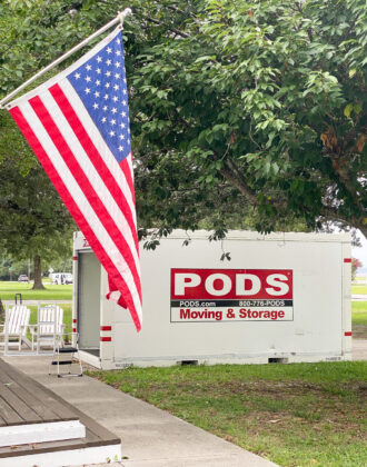 A PODS container sitting on the driveway of a military service member with an American flag sitting on the driveway