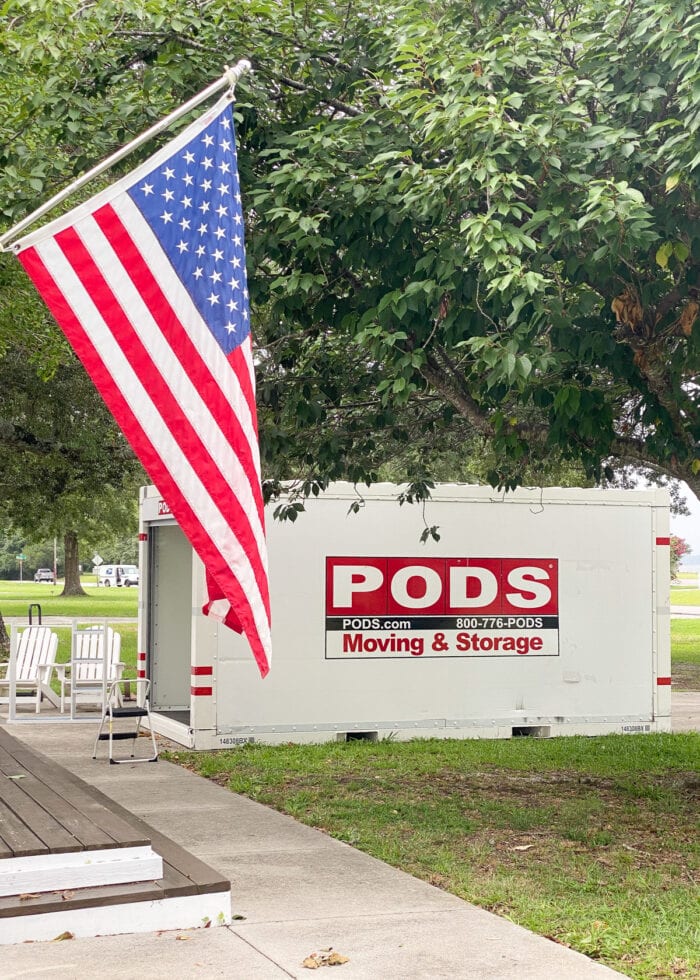 A PODS container sitting on the driveway of a military service member with an American flag sitting on the driveway