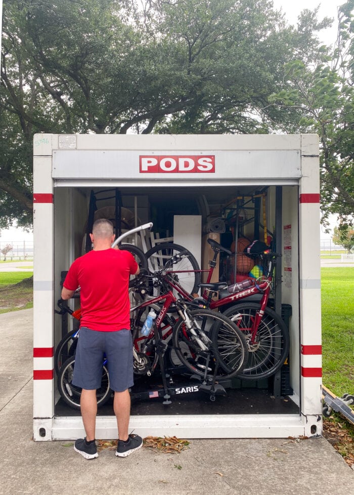 A PODS container filled to the front with items and bikes with a man in a red shirt securing things in place.