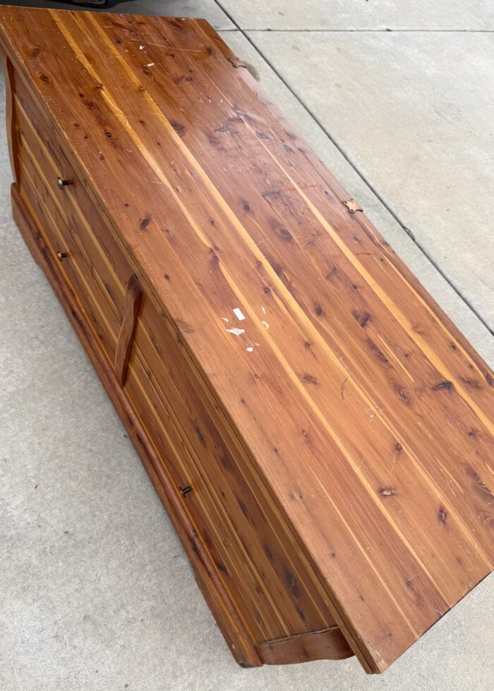 Vintage, old, damaged cedar chest sitting on a driveway