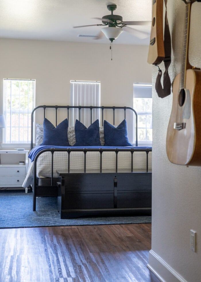 A master bedroom with an iron bed and a black cedar chest positioned at the end.