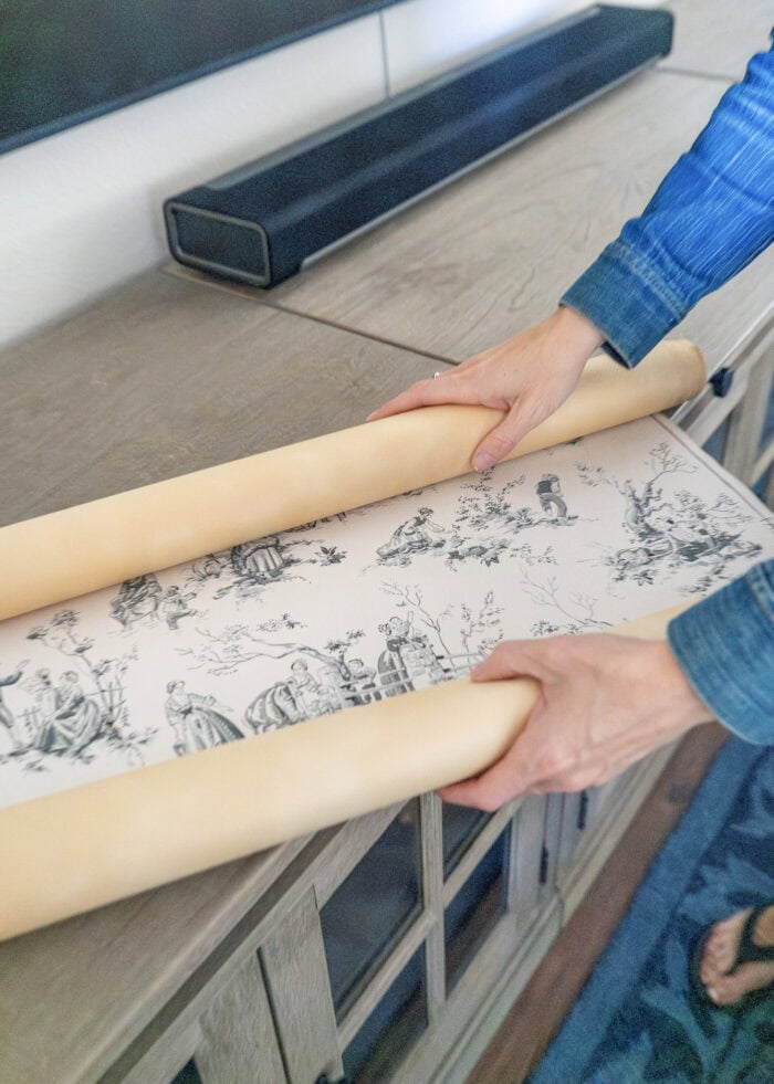Megan unrolling a roll of vintage wallpaper