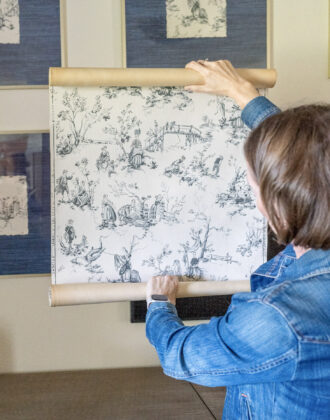 Megan holding up a roll of vintage wallpaper