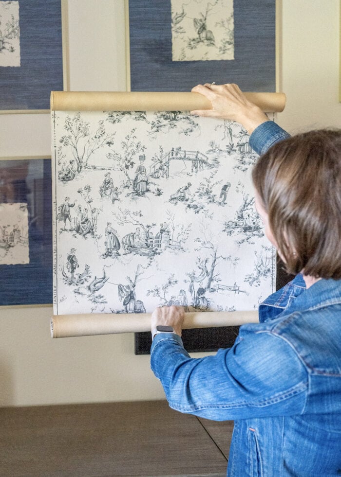 Megan holding up a roll of vintage wallpaper