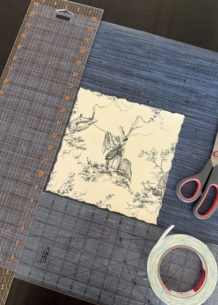 A piece of vintage wallpaper centered on a scrap of blue grasscloth wallpaper