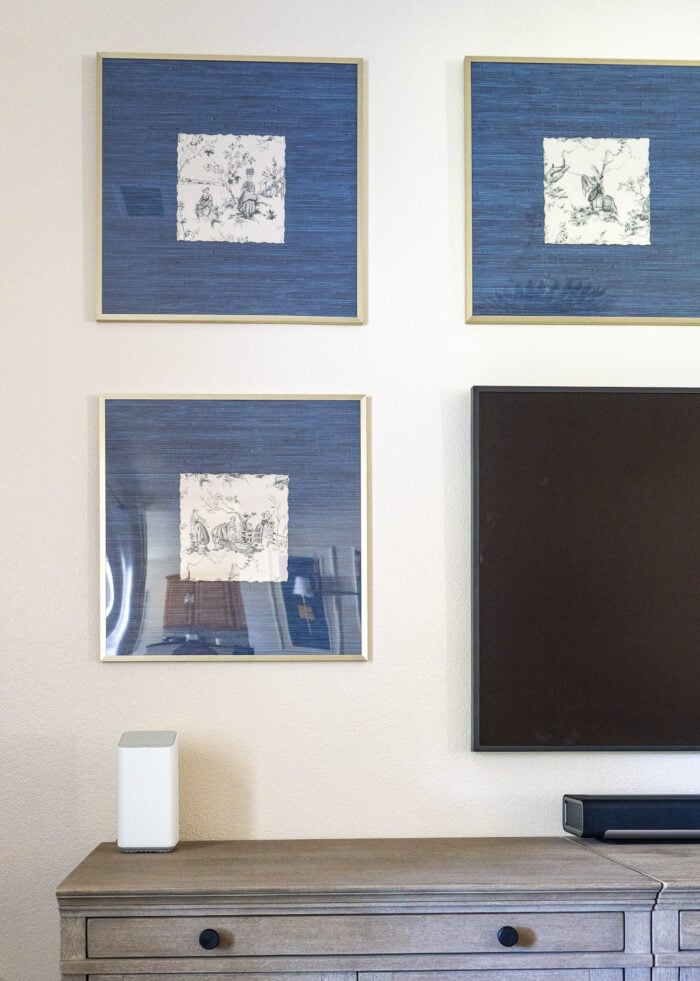 Gallery wall frames hung around a TV filled with scraps of vintage wallpaper as artwork