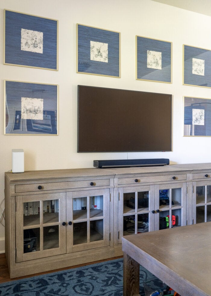 Gallery wall frames hung around a TV filled with scraps of vintage wallpaper as artwork