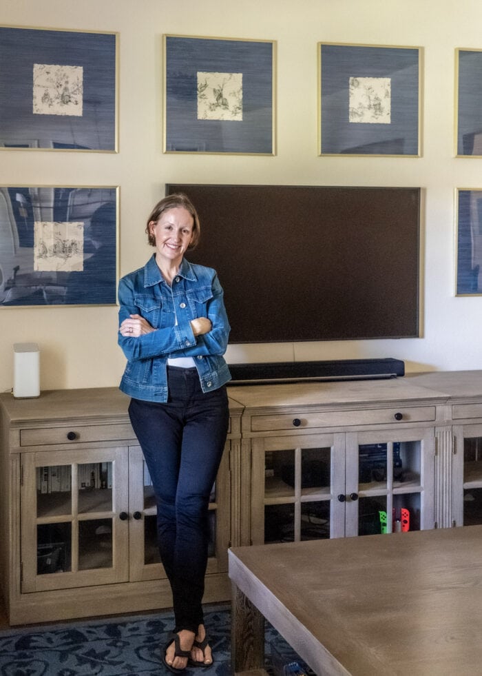 Megan standing in front of media cabinet and gallery wall around the TV