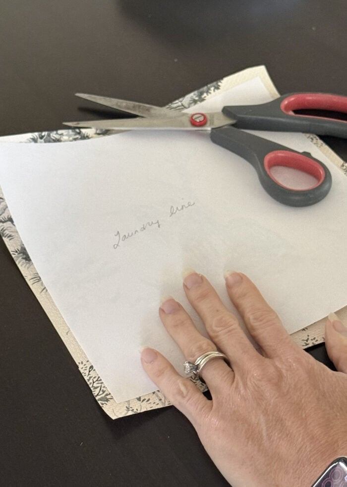 Hands cutting out a square of French vintage wallpaper