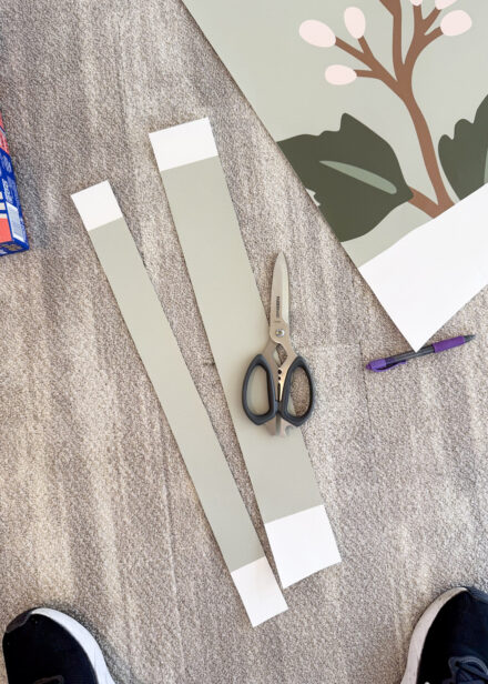 Two scraps of wallpaper cut into strips with a scissors and laying on the ground