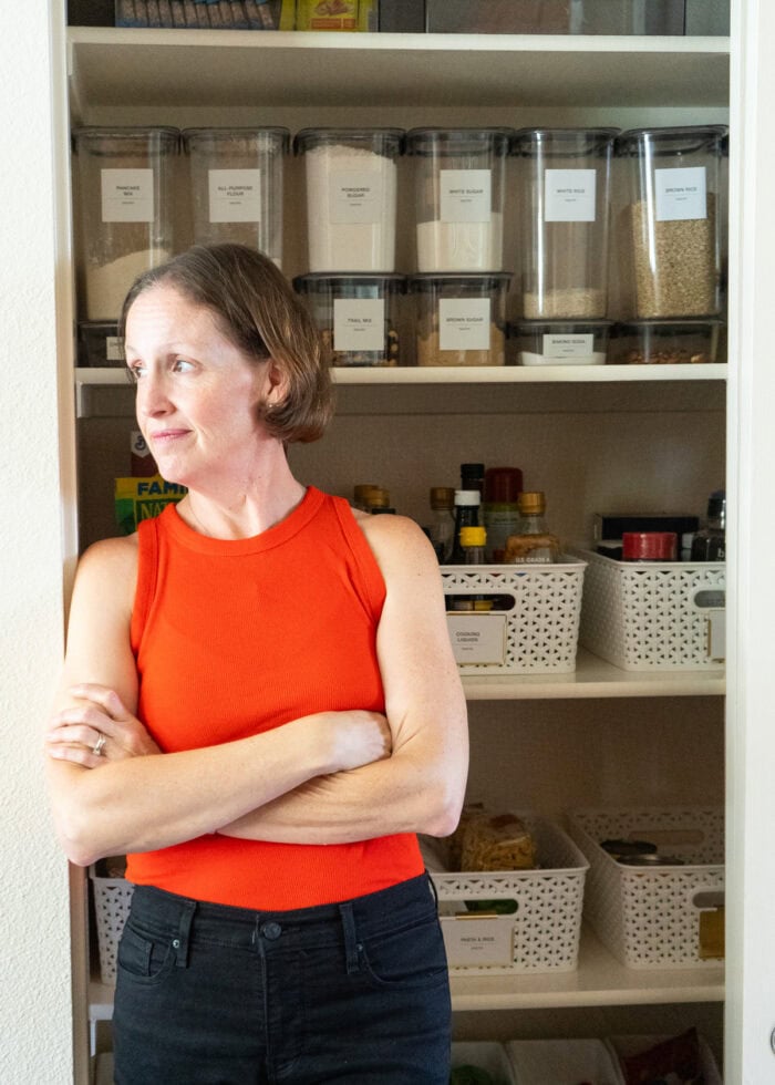 Megan in a red shirt standing near an open pantry