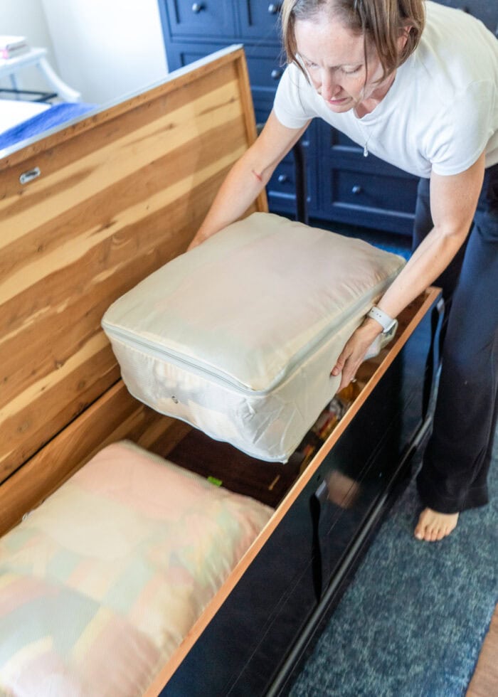 Megan placing a large compression sack into a cedar chest