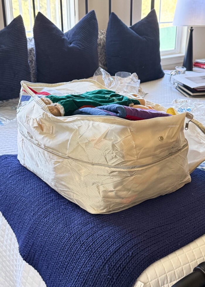 Compression bag filled up and sitting open on a bed.