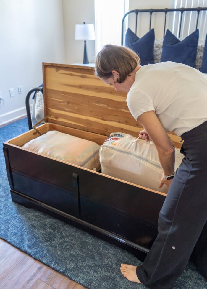 Megan placing a large compression sack into a cedar chest