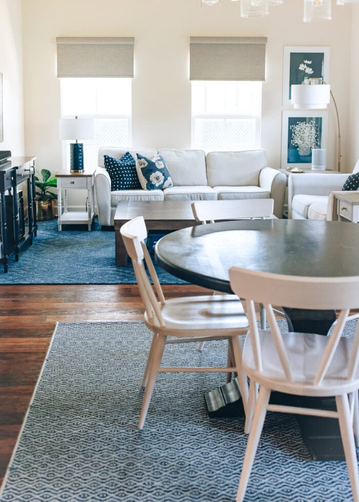 A combined living room and dining room arranged with cream furniture and dining chairs and blue accents.