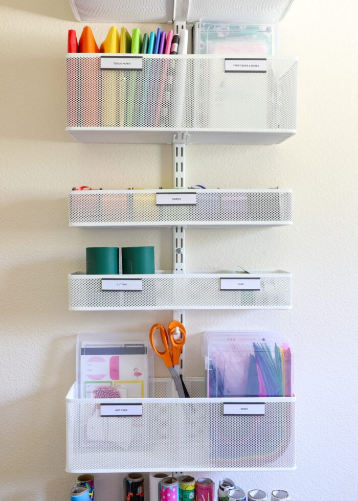 An Elfa storage rack mounted to a wall filled with gift wrapping supplies