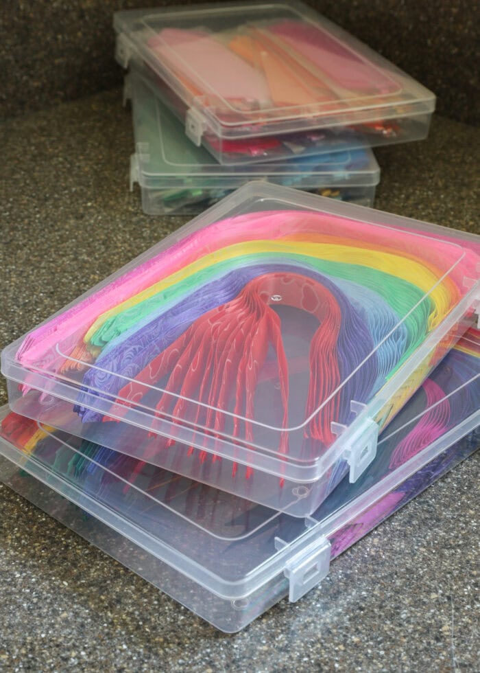 Dozens of colorful pull bows stored flat in small plastic cases