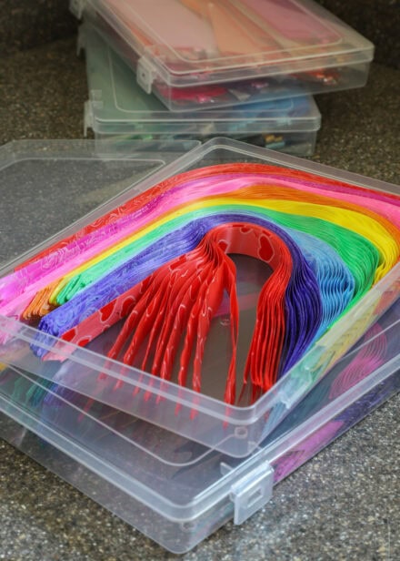 Dozens of colorful pull bows stored flat in small plastic cases