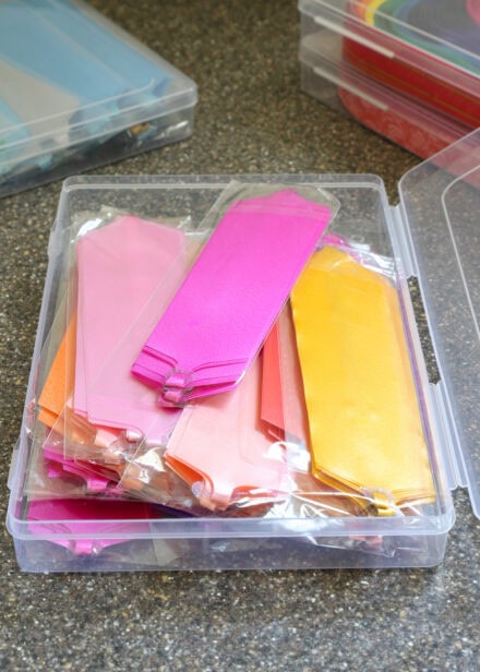 A plastic case holding dozens of large pull bows in a variety of warm colors
