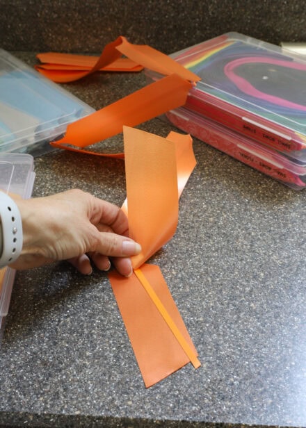 Hand opening the pull bow to reveal a ribbon between the layers