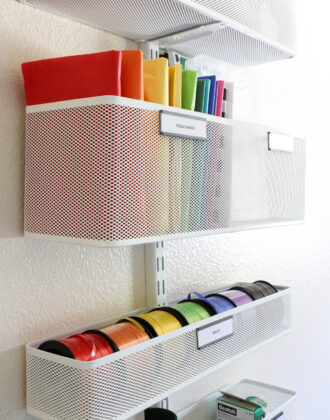 Raibow assortment of tissue paper and ribbon stored in an Elfa storage system mounted to the wall