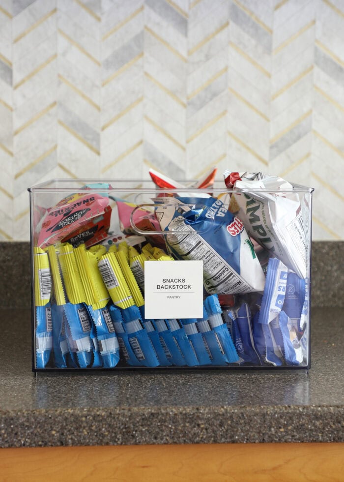A clear container sitting on a kitchen counter holding pantry backstock