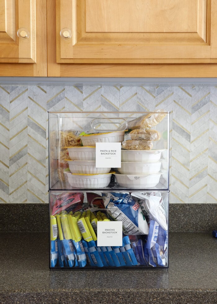 Two clear containers sitting on a kitchen counter holding pantry backstock