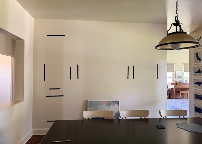 A round light fixture hung over a dining table not centered