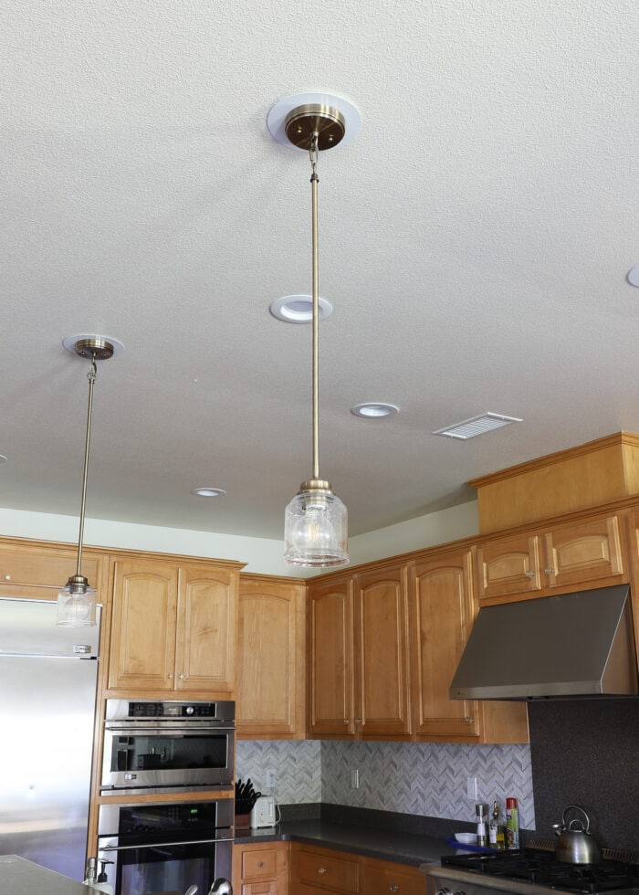 Two brass pendant lights hung over a kitchen island
