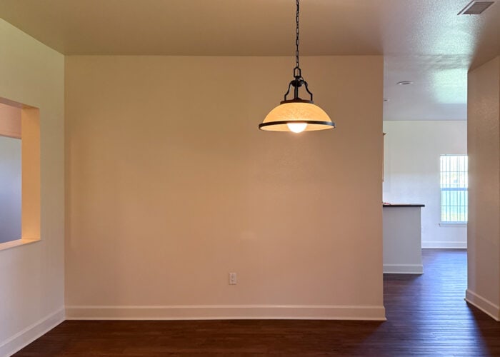 An empty rental dining room with an ugly pendant light fixture hung off center