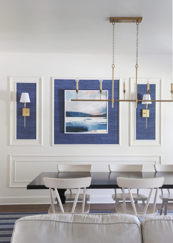 A dining room with a gold, rectangular shaped light fixture hung above the table