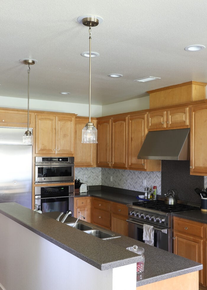 Two brass pendant lights hung over a kitchen island